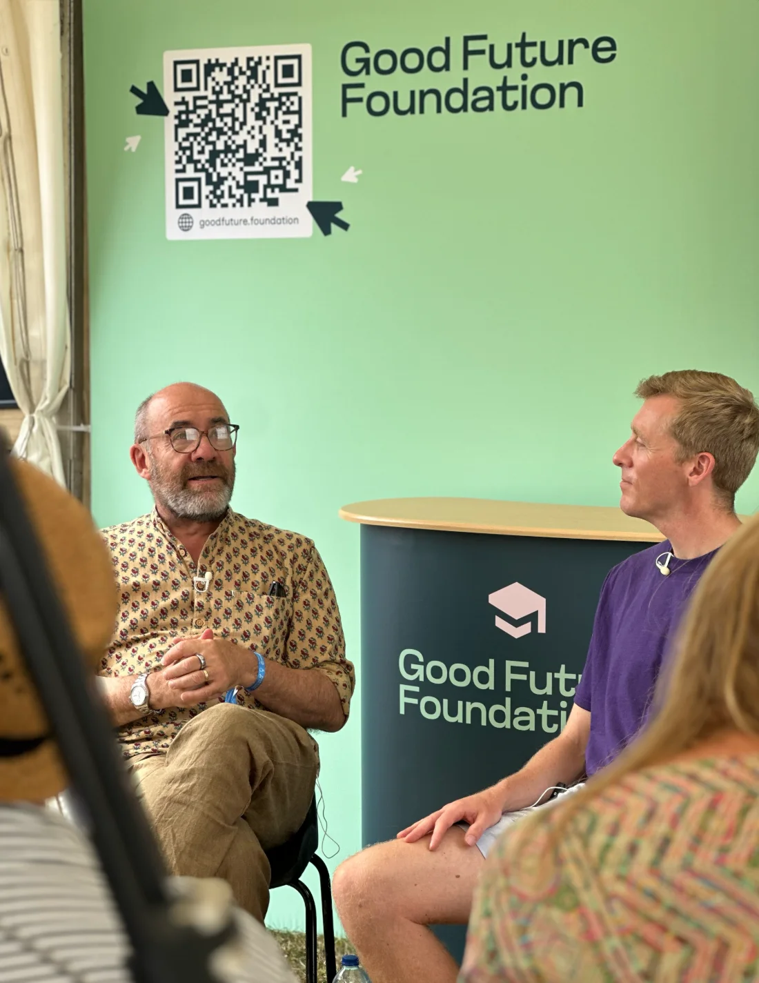 A Good Future Foundation talk at a festival, in front of the branded backdrop and lectern